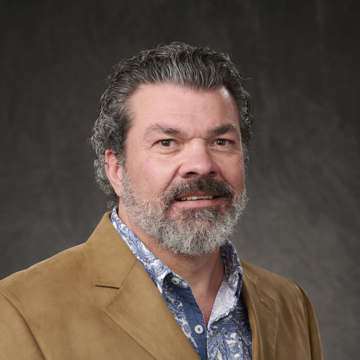 A man with a beard and mustache wearing a jacket.