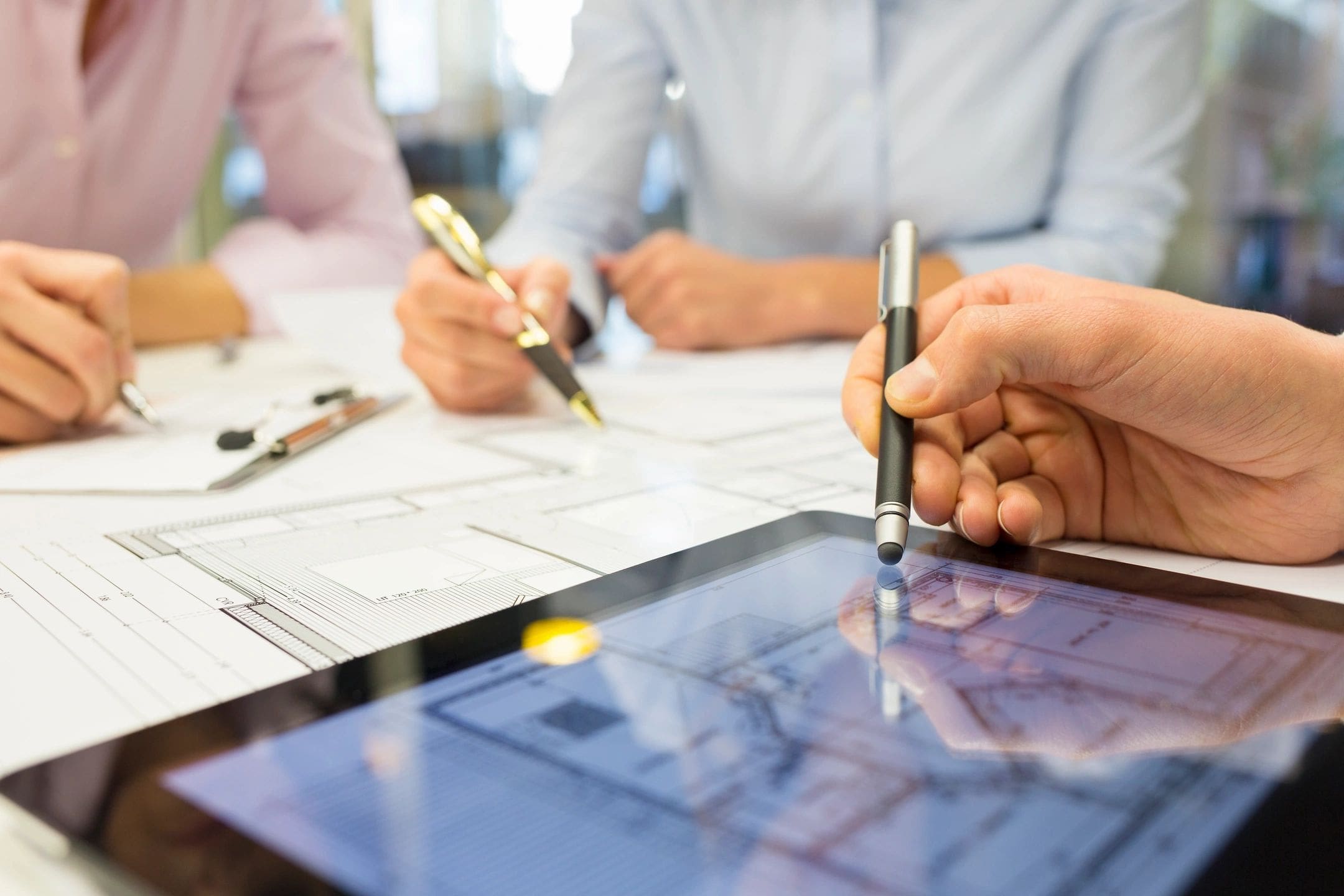 A group of people sitting around a table with pens and papers.