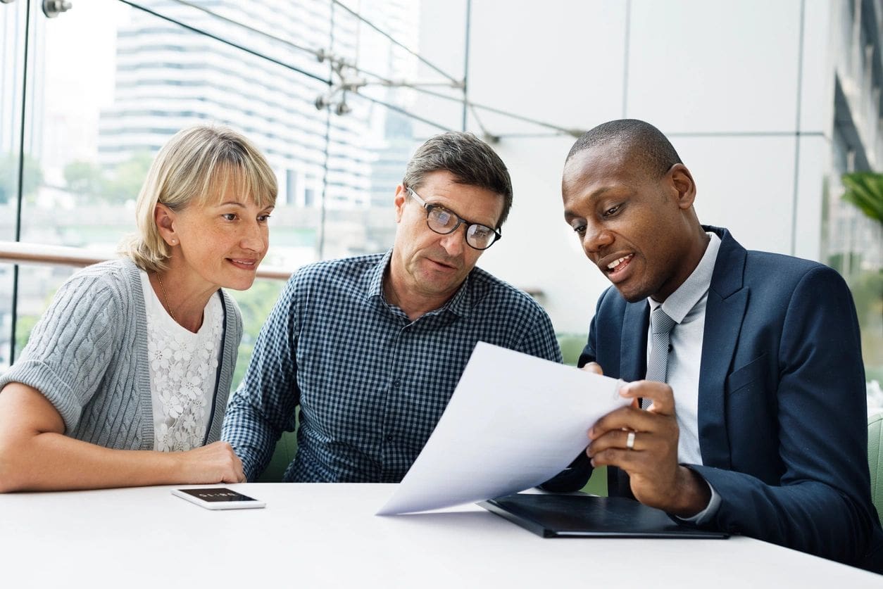 A man and two women looking at papers.