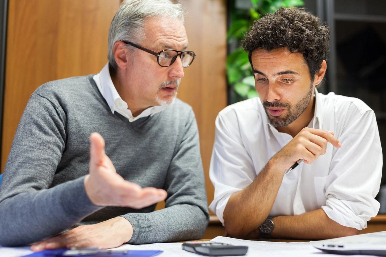 Two men are sitting at a table talking.